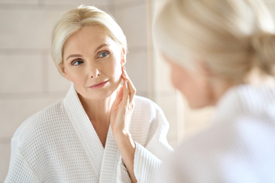 woman in white robe looking into mirror
